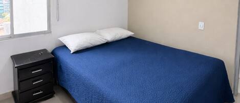 Un dormitorio con cama, mesita de noche, ventana y lámpara de techo.