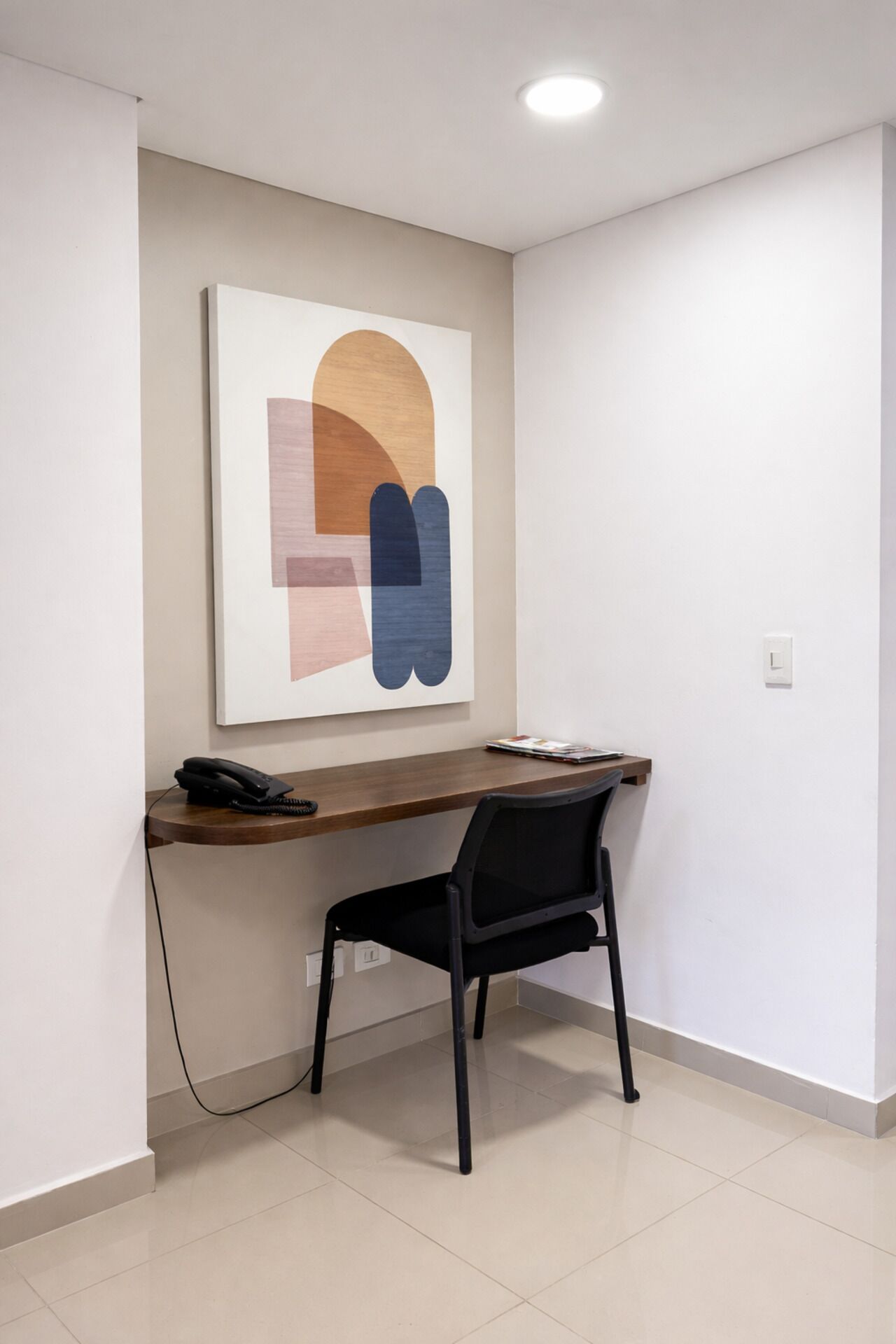 Un espace de bureau moderne comprenant un bureau, une chaise et un grand tableau abstrait accroché au mur.
