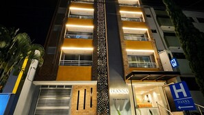 Een hotel met een moderne gevel, meerdere balkons en een opvallende verticale lichtaccent.