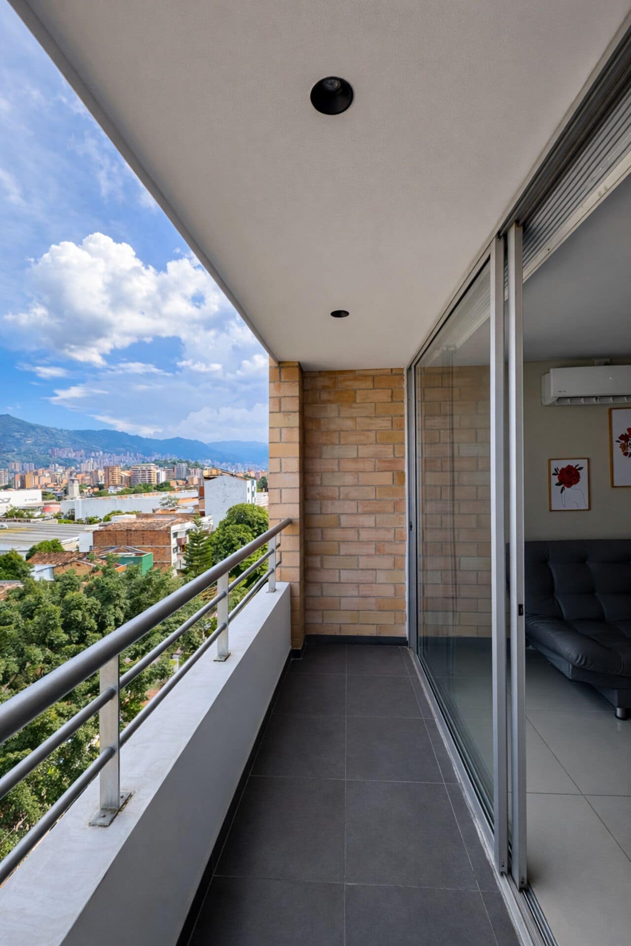 Un balcone con vista sulla città, una porta in vetro e un divano.