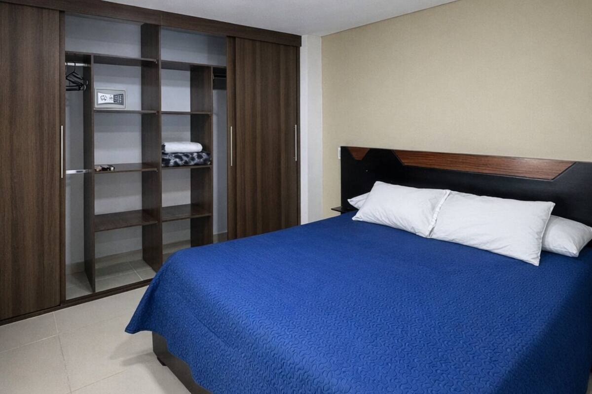 Een slaapkamer met een bed, een kledingkast en een plafondlamp.