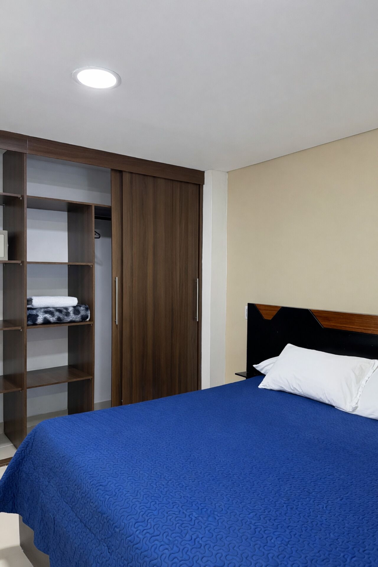A bedroom with a bed, a wardrobe, and a ceiling light.