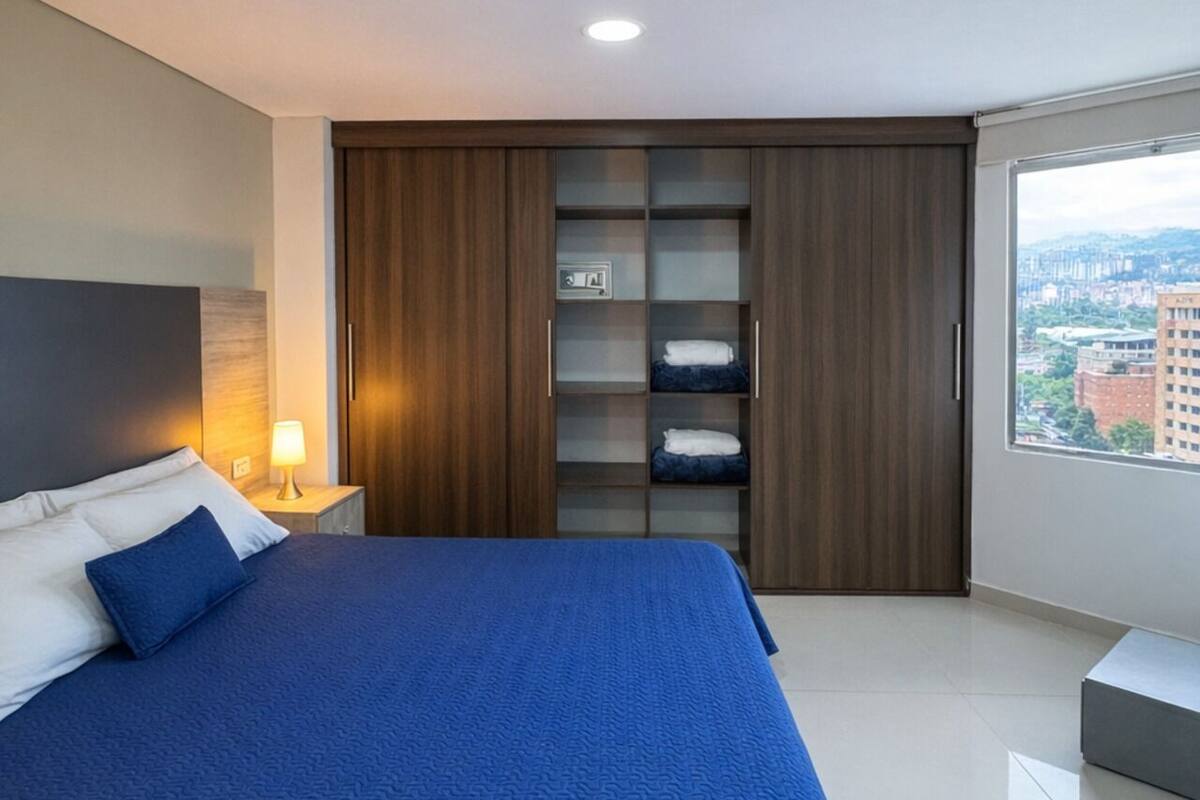Een moderne slaapkamer met een groot bed, een inbouwkleerkast en uitzicht op de stad.