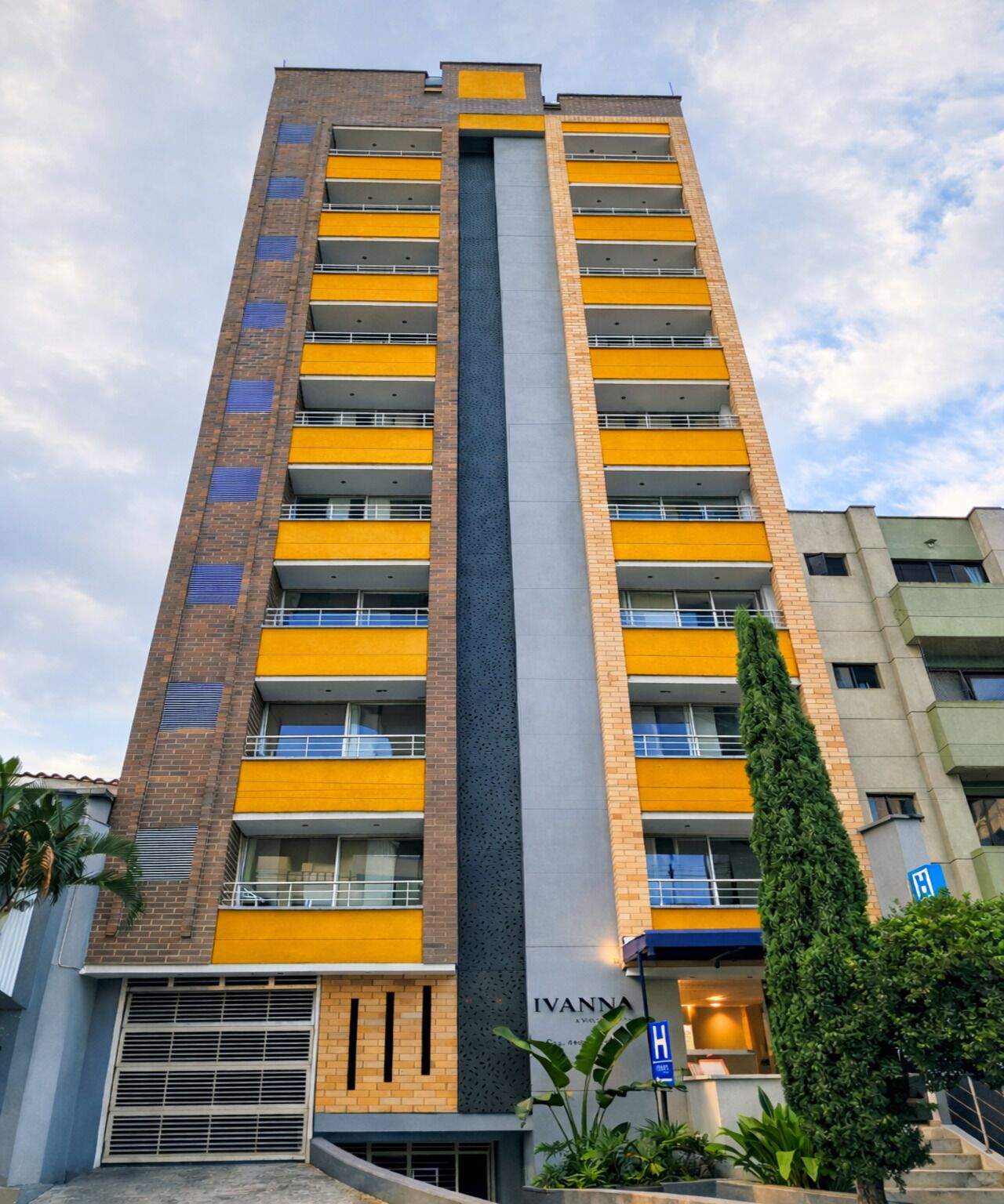 A tall, modern building with multiple balconies and a prominent central column.