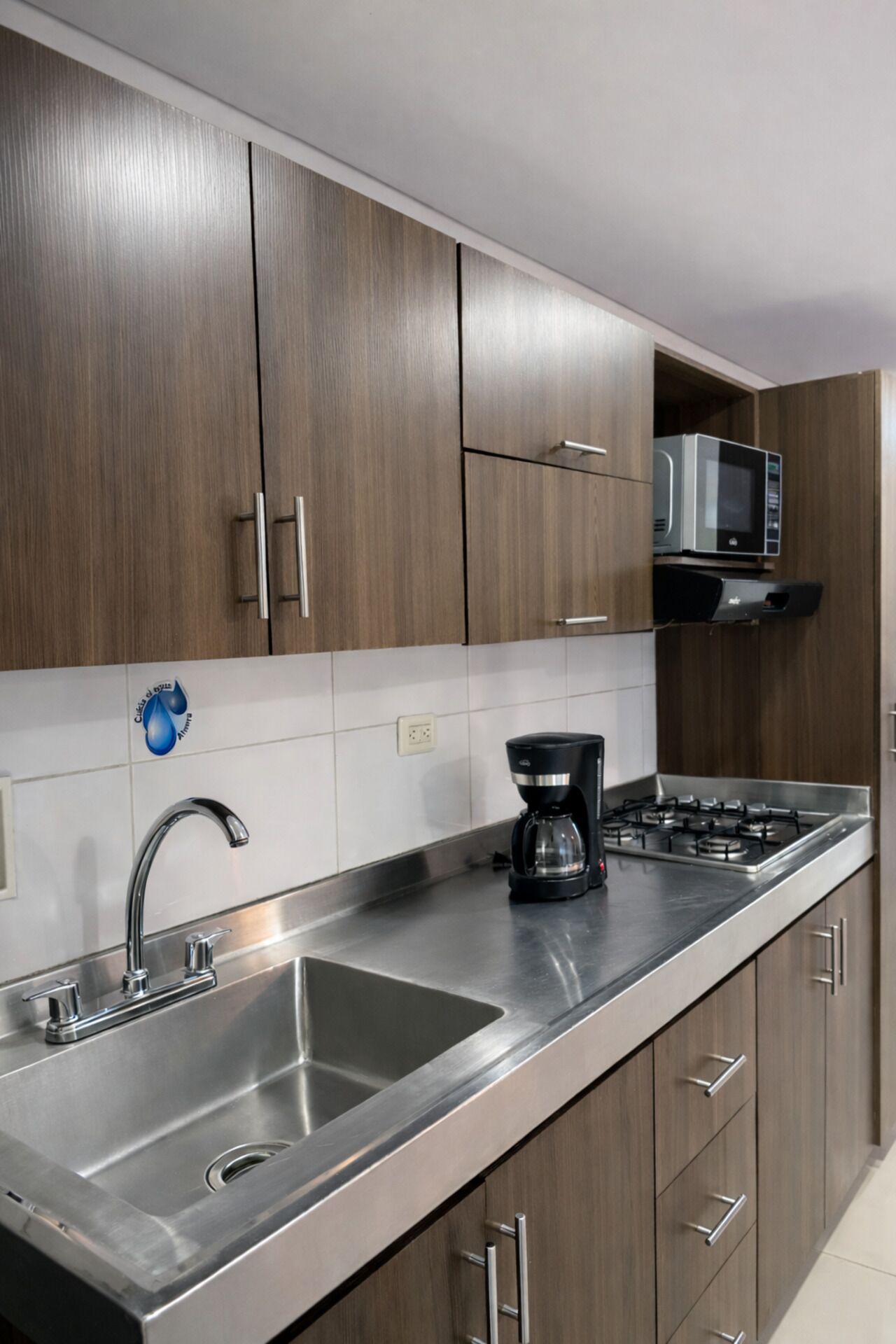 Una cocina moderna con electrodomésticos de acero inoxidable, cafetera y armarios de madera.