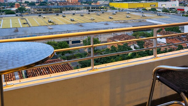 Een balkon met uitzicht op een stadsbeeld, inclusief gebouwen en een bergketen.