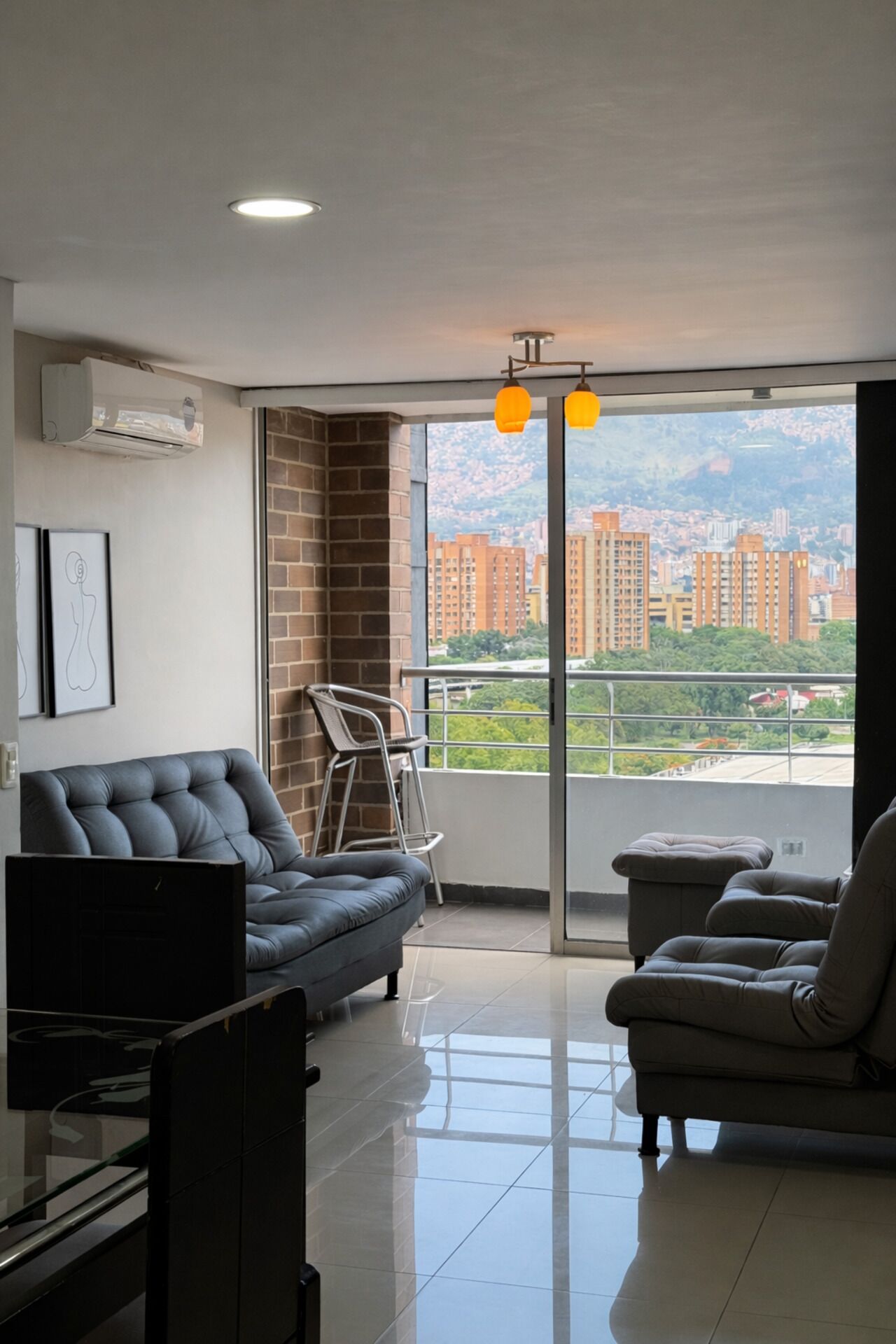 A modern living room with a sofa, a chair, a TV, and a balcony with a city view.