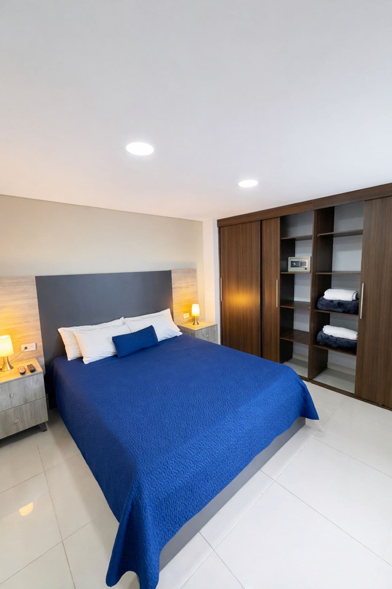 Un dormitorio moderno con una cama grande, una mesita de noche, un armario y un televisor integrado.