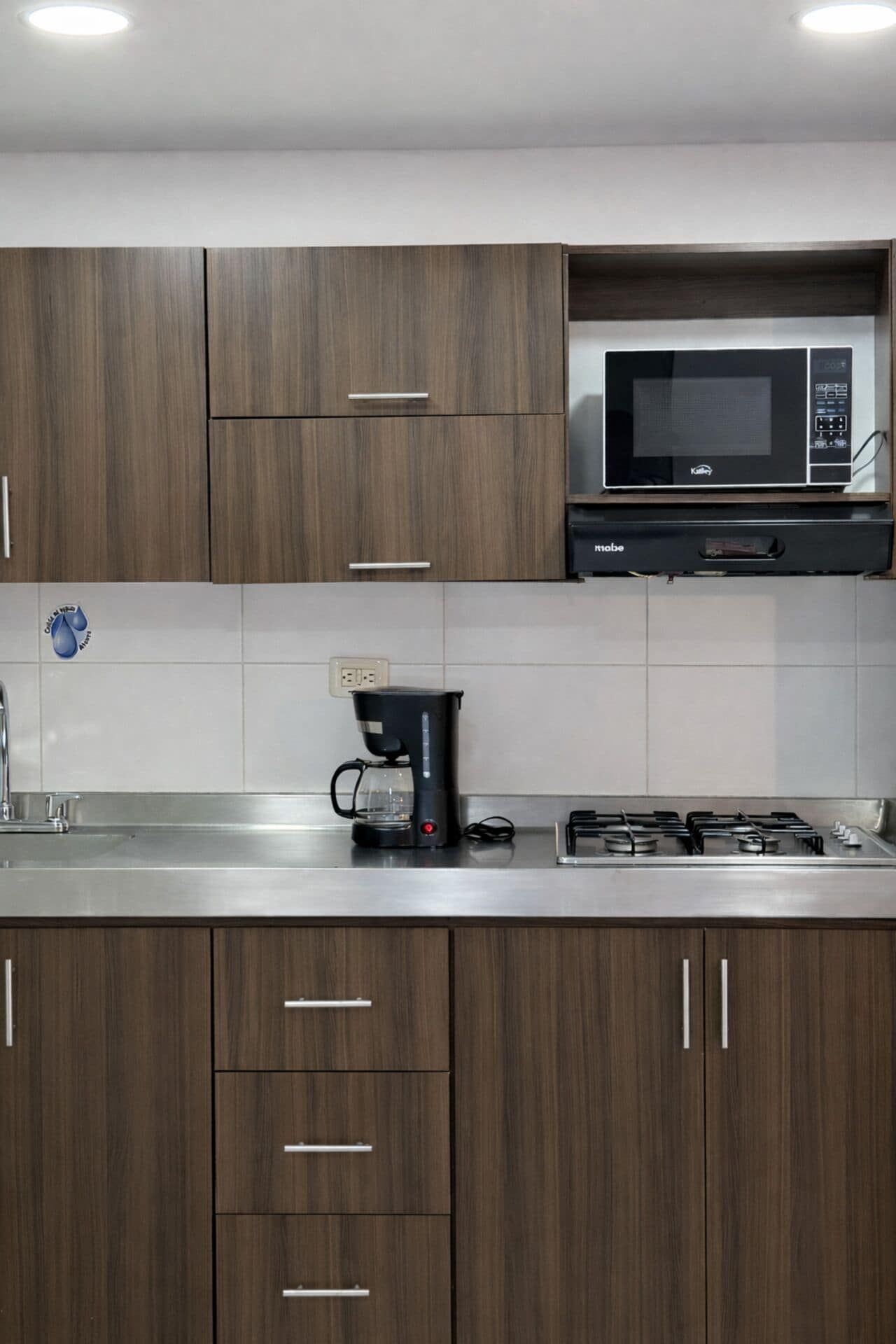 A modern kitchen with wooden cabinets, a coffee maker, a microwave, and a gas stove.
