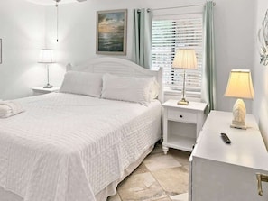 A neatly arranged bedroom with a bed, bedside tables, and a lamp.