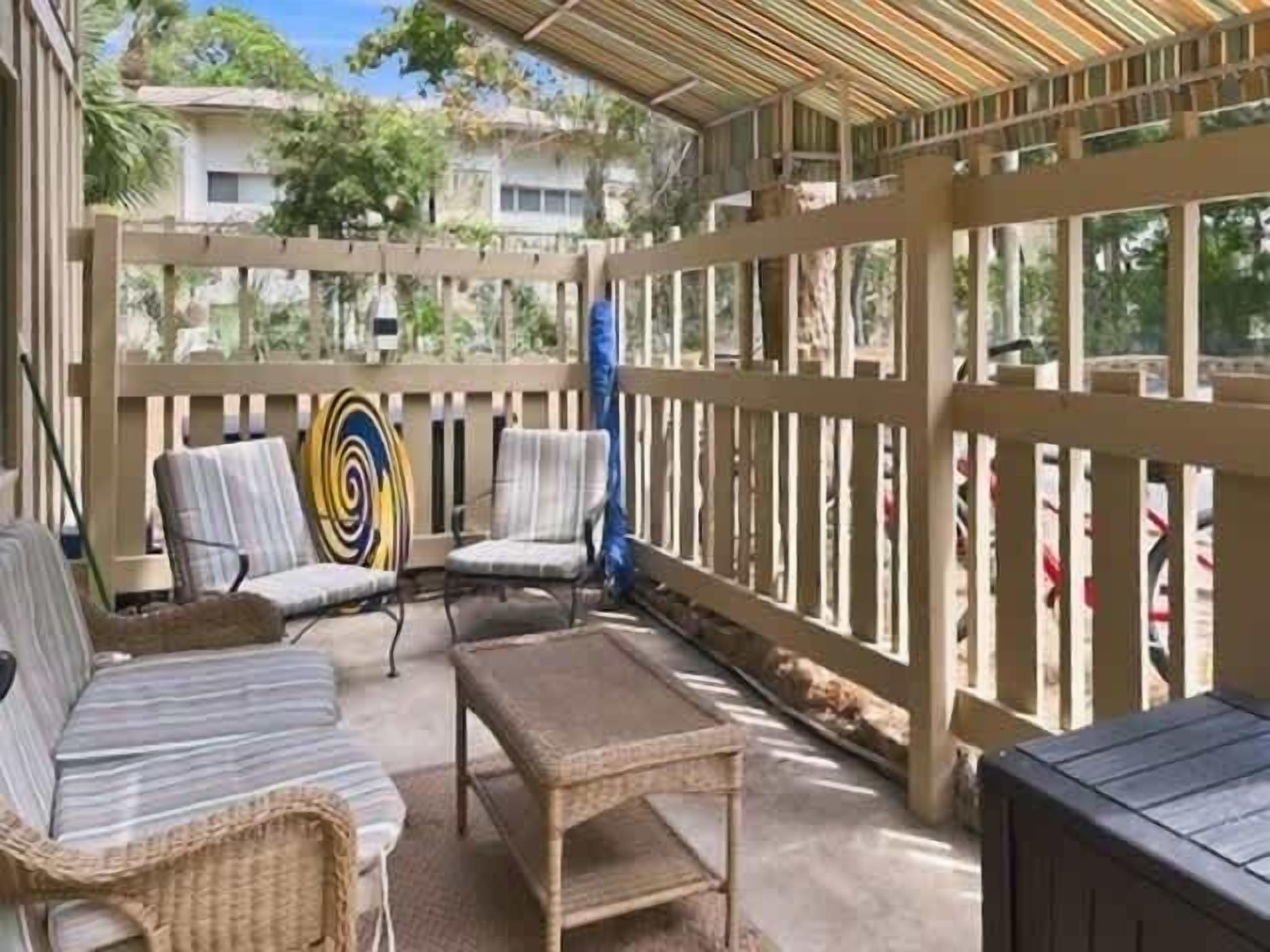Un espacio al aire libre cubierto con mobiliario de mimbre y una valla de madera.