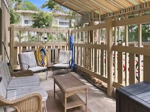 A covered outdoor seating area with wicker furniture and a wooden fence.