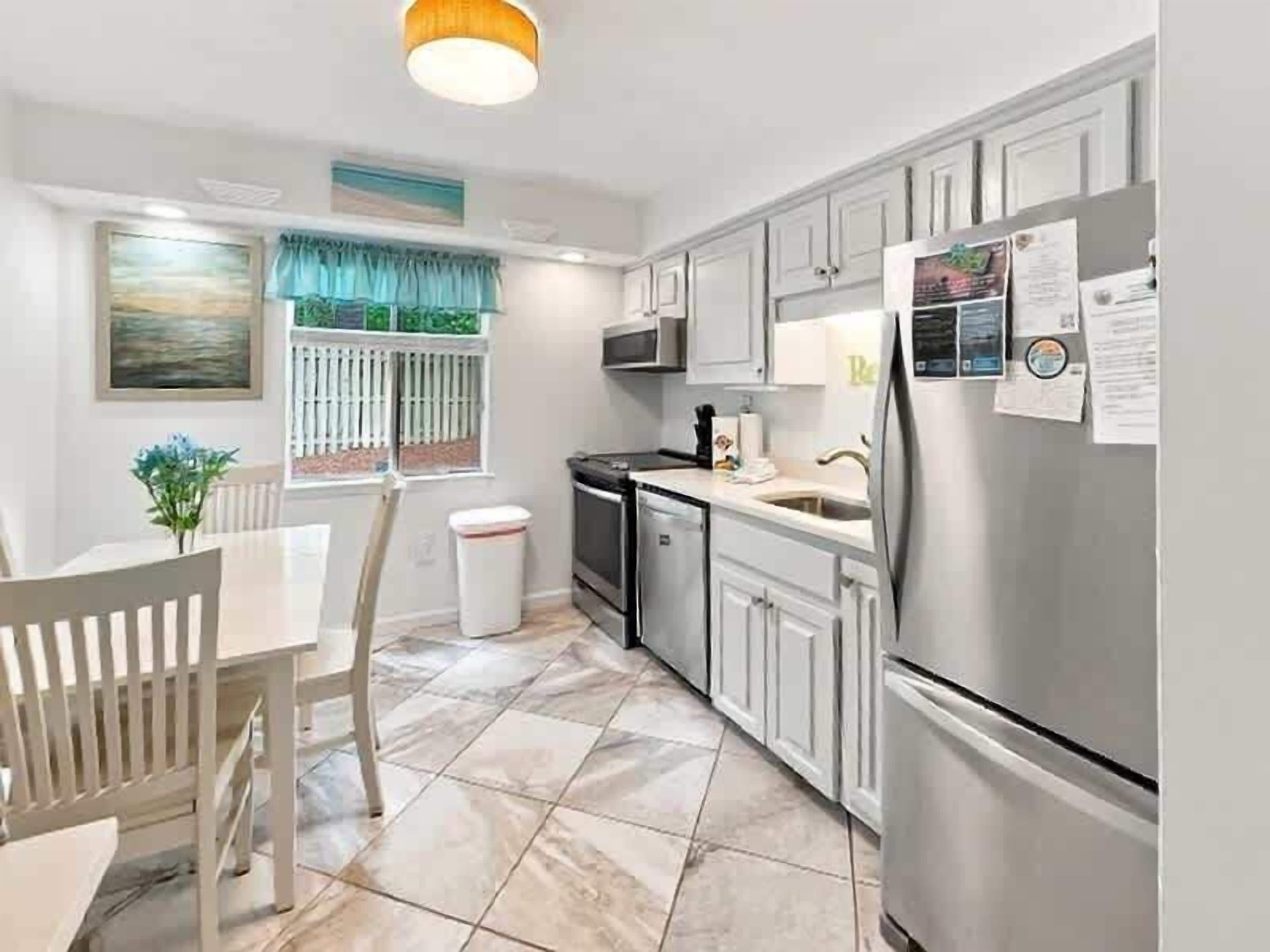 A kitchen with white cabinets, a stainless steel refrigerator, and a tiled floor.
