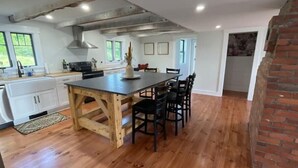 A kitchen with a wooden island, white cabinets, and a brick wall. - Dog Friendly, Modern Retreat w/ Stunning View (Freedom)
