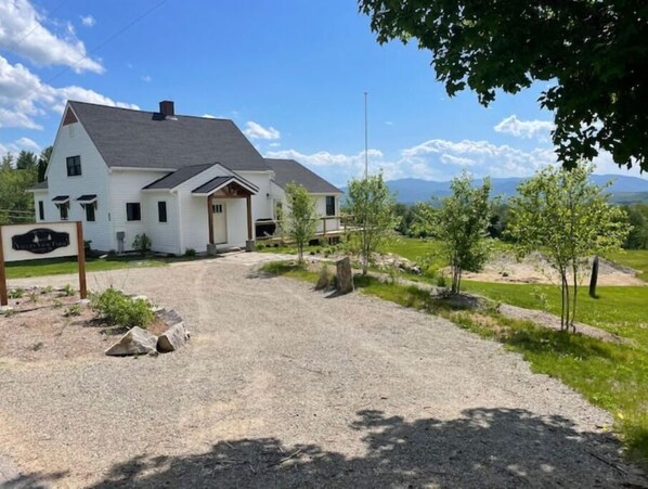 A two-story white house with a dark roof, a front porch, and a gravel driveway. - Dog Friendly, Modern Retreat w/ Stunning View (Freedom)