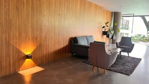 A modern interior with a wooden panel wall, a grey sofa, a small table, and a potted plant. - Spacious loft at amazing location! (sabaneta)