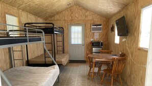 Habitación compacta con literas, una pequeña cocina y una mesa de comedor.