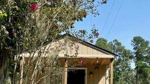 Una pequeña cabaña de madera con porche y mesa de picnic.