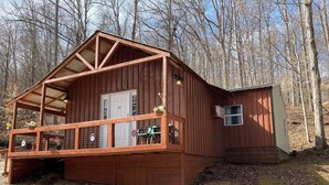 Eine Holzhütte mit Veranda, einer Tür und einem kleinen Anbau.