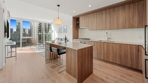 Una cocina moderna con armarios de madera, una isla central y vistas a la ciudad a través de amplios ventanales.