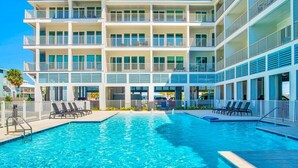 Un hôtel à plusieurs étages doté d’une piscine centrale, d’un espace extérieur aménagé et de balcons.