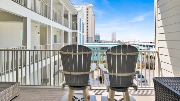 Un balcon avec deux fauteuils Adirondack, une vue sur le paysage urbain et un immeuble à étages multiples doté de balcons.