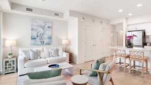 Un salon moderne avec un canapé blanc, une table basse et un coin repas doté de chaises en osier.