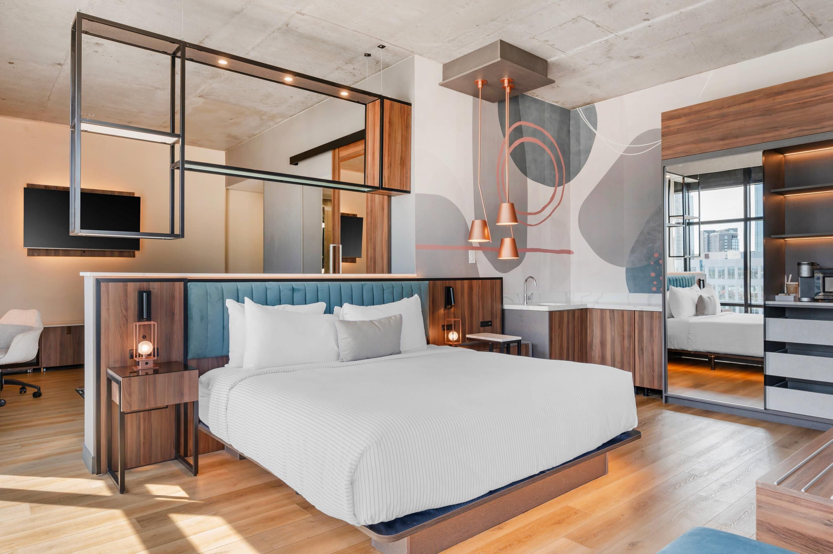 A modern bedroom with a large bed, bedside tables, a mirror, and a built-in wardrobe.