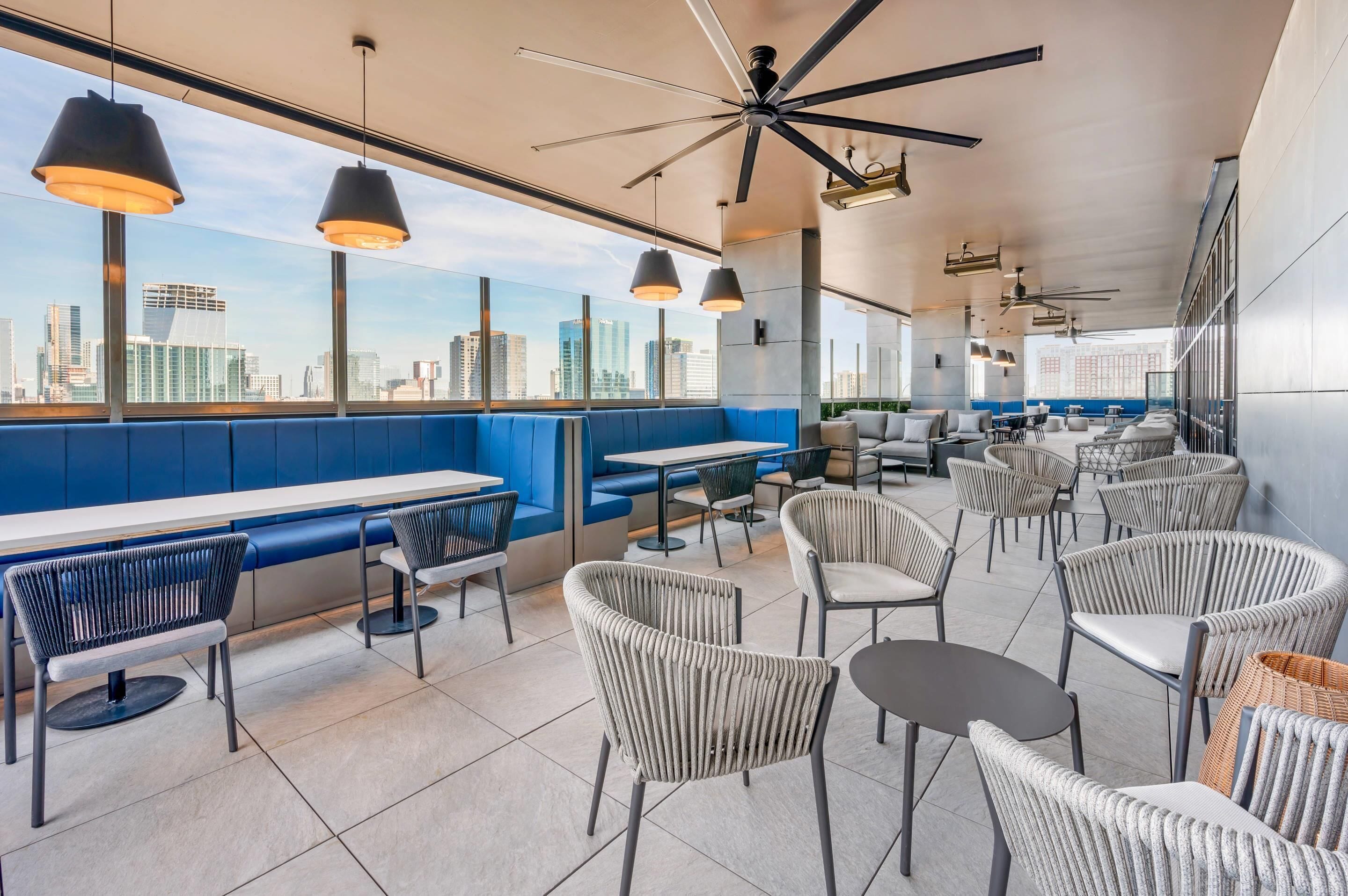 Un restaurante moderno con techos altos, amplias ventanas y vista a la ciudad.