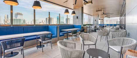 Un restaurante moderno con techos altos, amplias ventanas y vista a la ciudad.