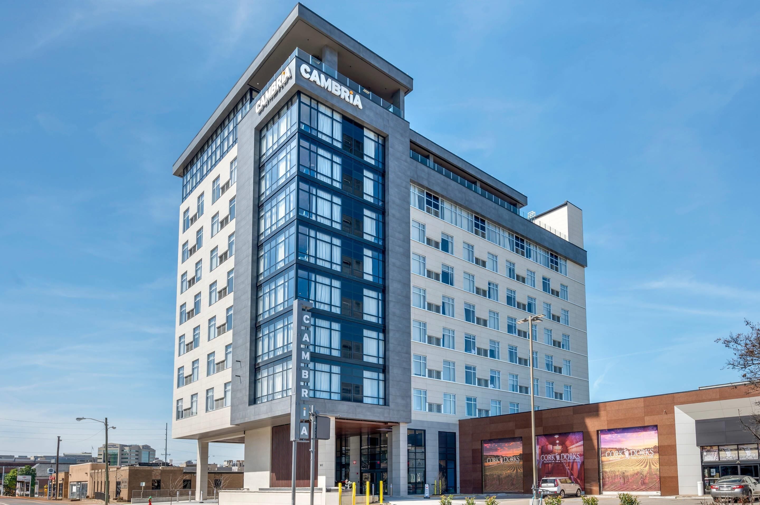 A modern multi-story hotel with a prominent 'CAMBRIA' sign, large windows, and a visible entrance.