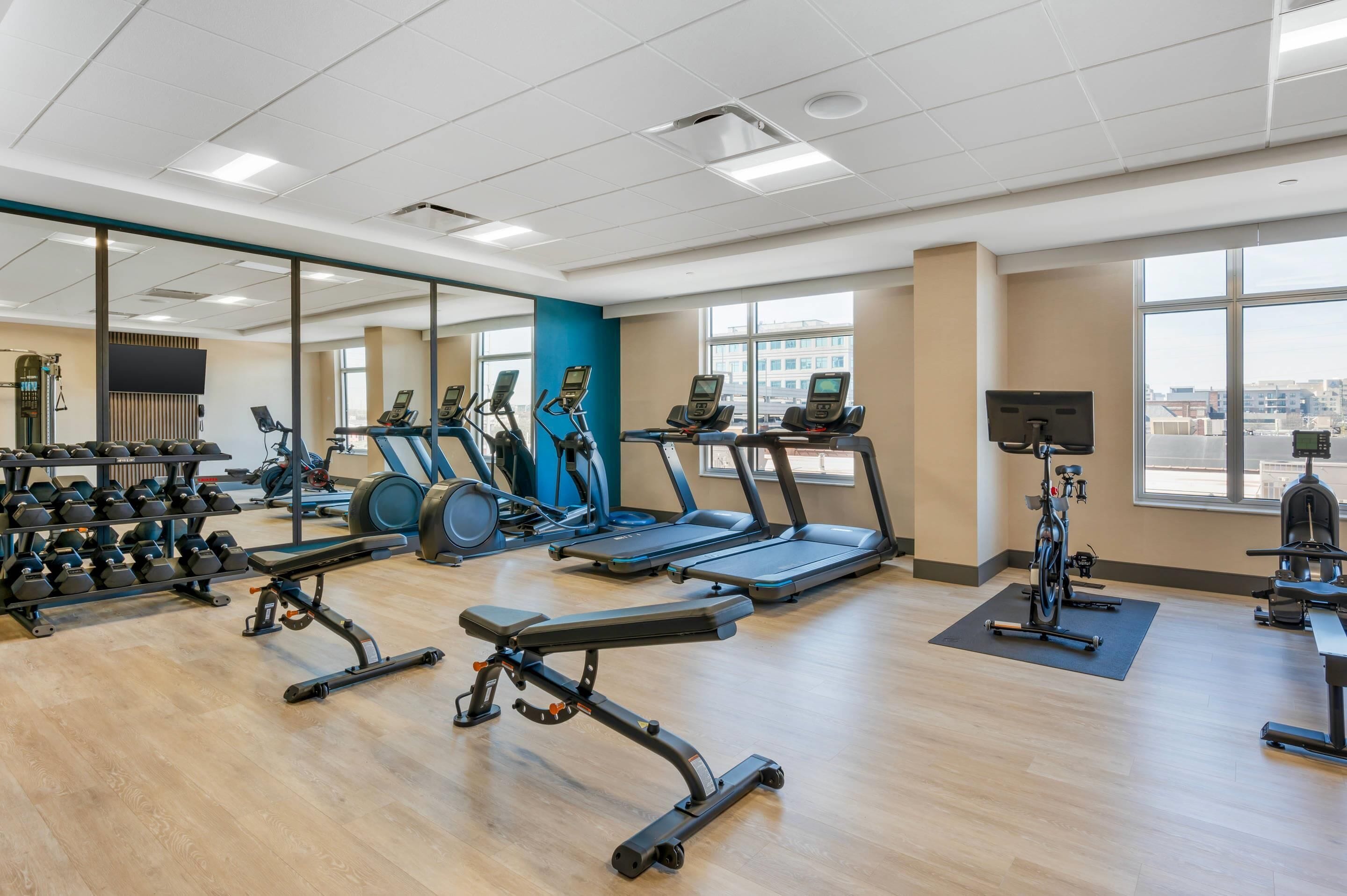 A gym with treadmills, elliptical machines, and free weights.