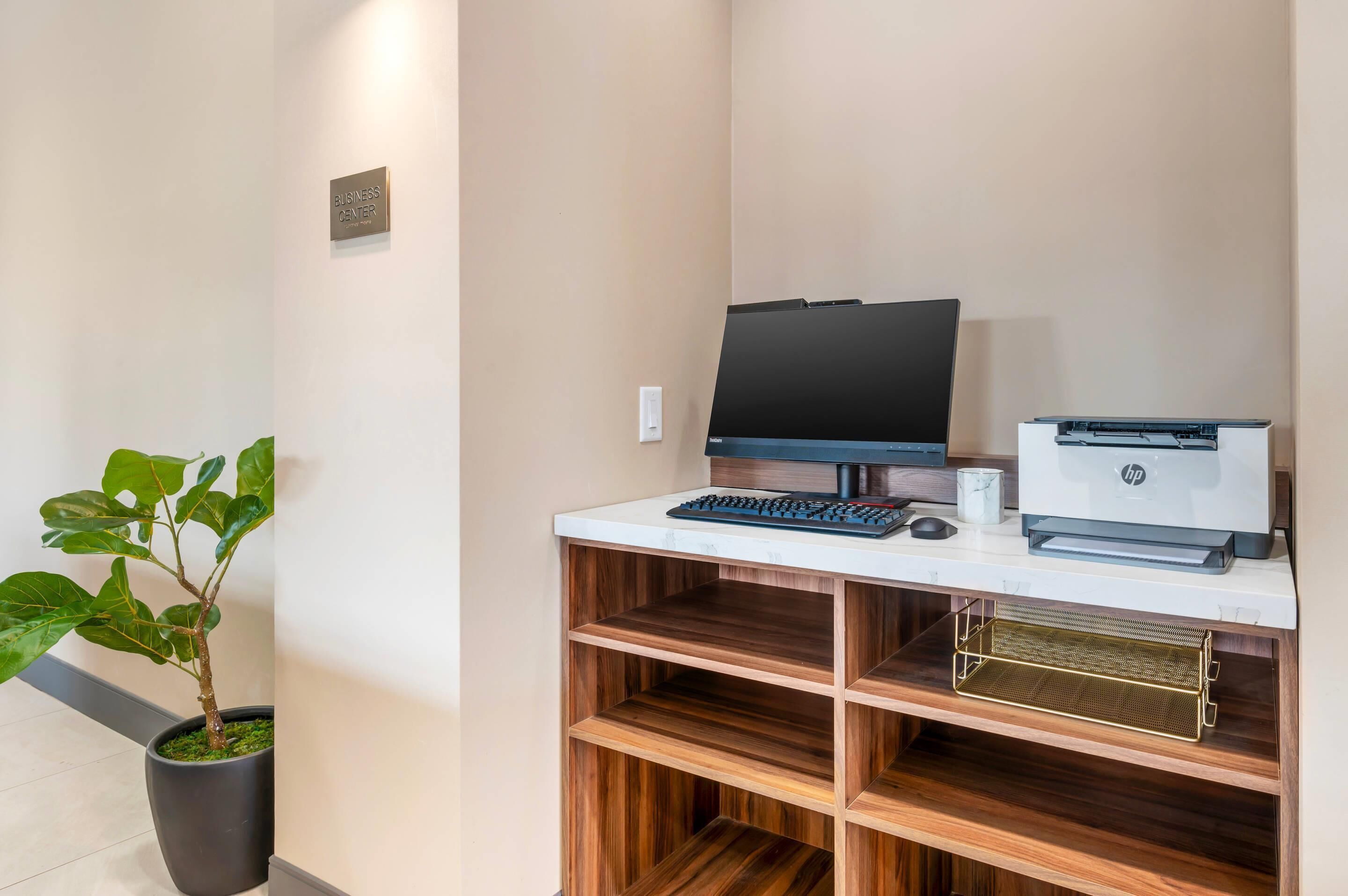A workspace with a computer, keyboard, and HP printer on a white desk.