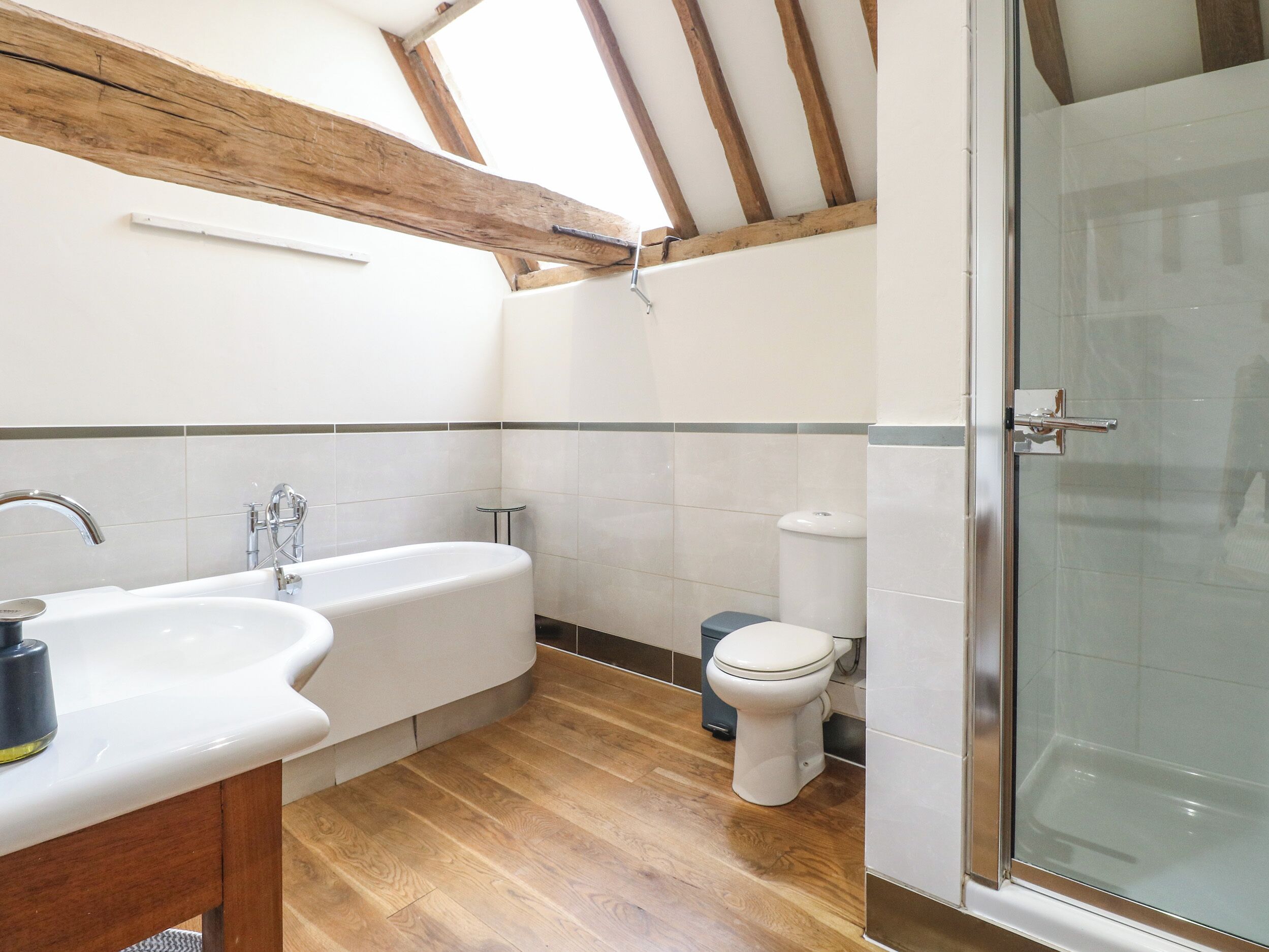 A bathroom with a bathtub, sink, toilet, and glass shower enclosure.