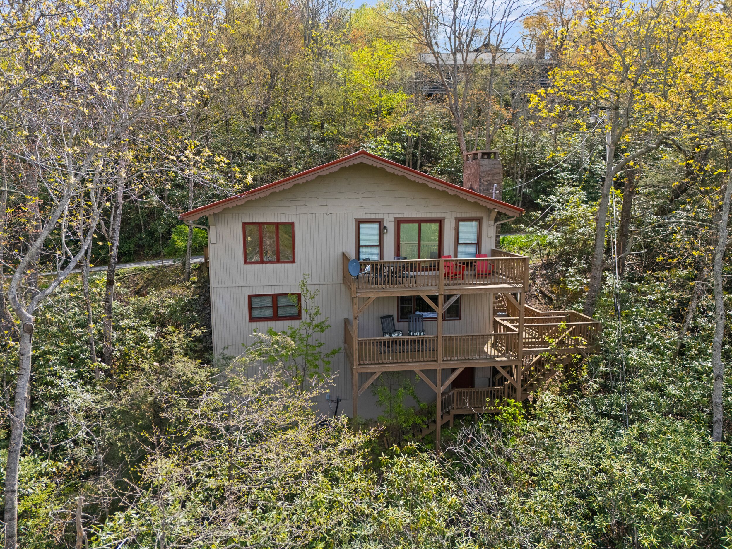 A two-story cabin with a balcony, surrounded by dense forest.