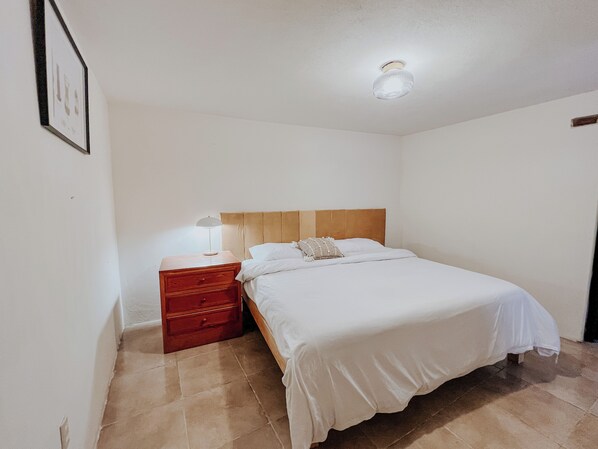 A bedroom with a bed, a nightstand, a lamp, and a ceiling light fixture.