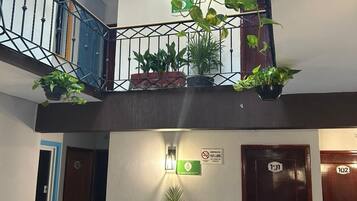 A multi-level indoor space with a staircase, potted plants, and doors labeled 121 and 122.