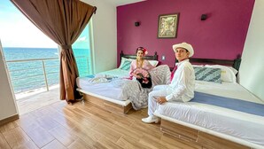 A room with two beds, a large window with curtains, a view of the sea, and a purple wall. - Hotel Jar8 Bule (Boca del Río)