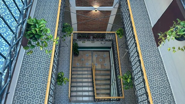 A modern interior with a central staircase, patterned flooring, and metal railings. - Hotel Jar8 Bule (Boca del Río)