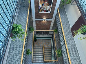 Un interior moderno con una escalera central, suelo estampado y barandillas de metal.