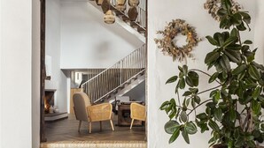 A modern interior with a staircase, wicker furniture, and a potted plant.