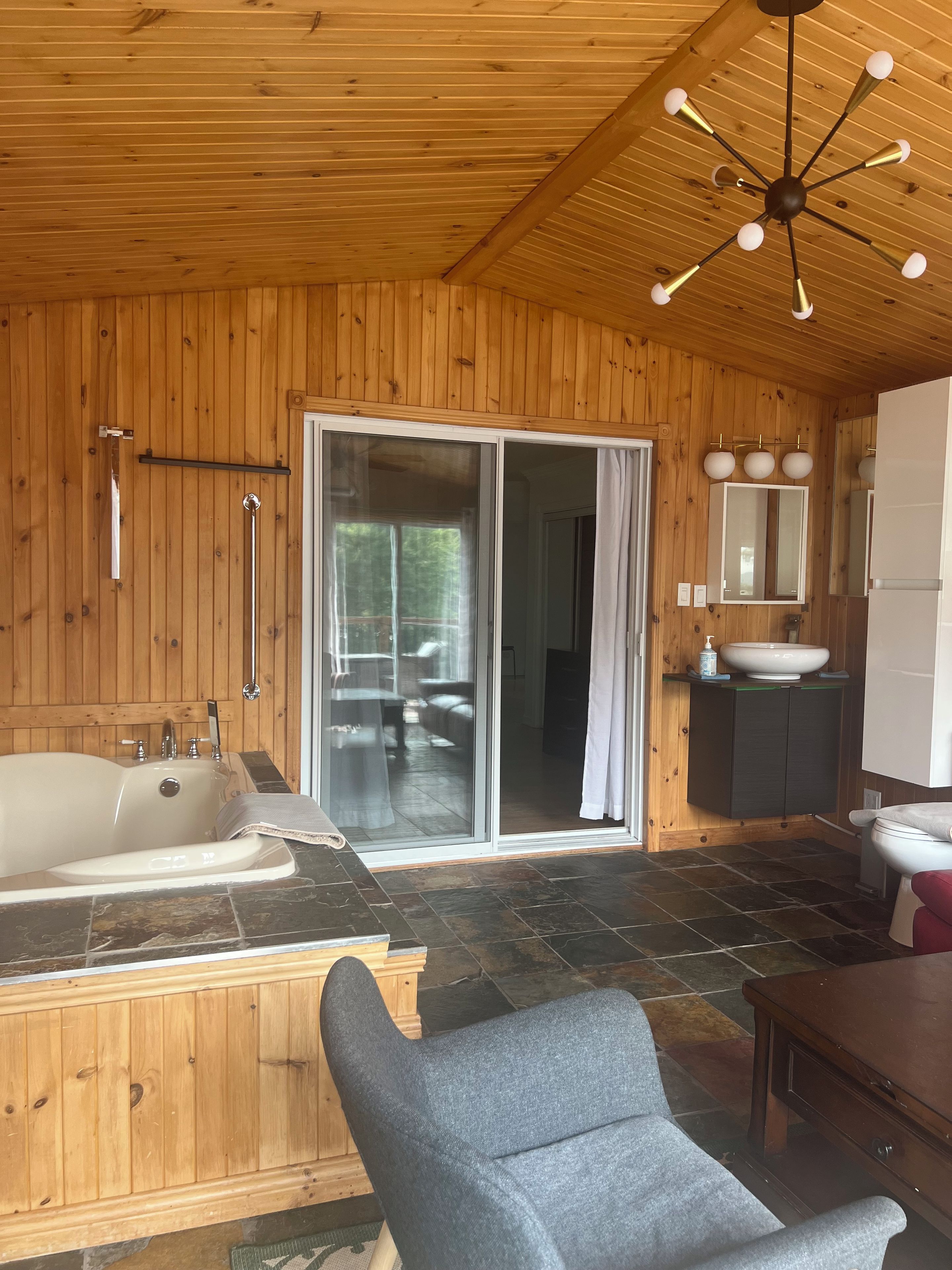 A wooden interior with a bathtub, a shower, a sink, and a mirror.