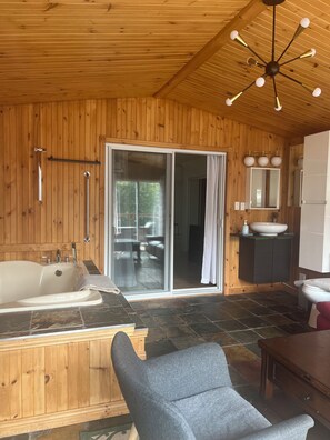 A wooden interior with a bathtub, a shower, a sink, and a mirror.