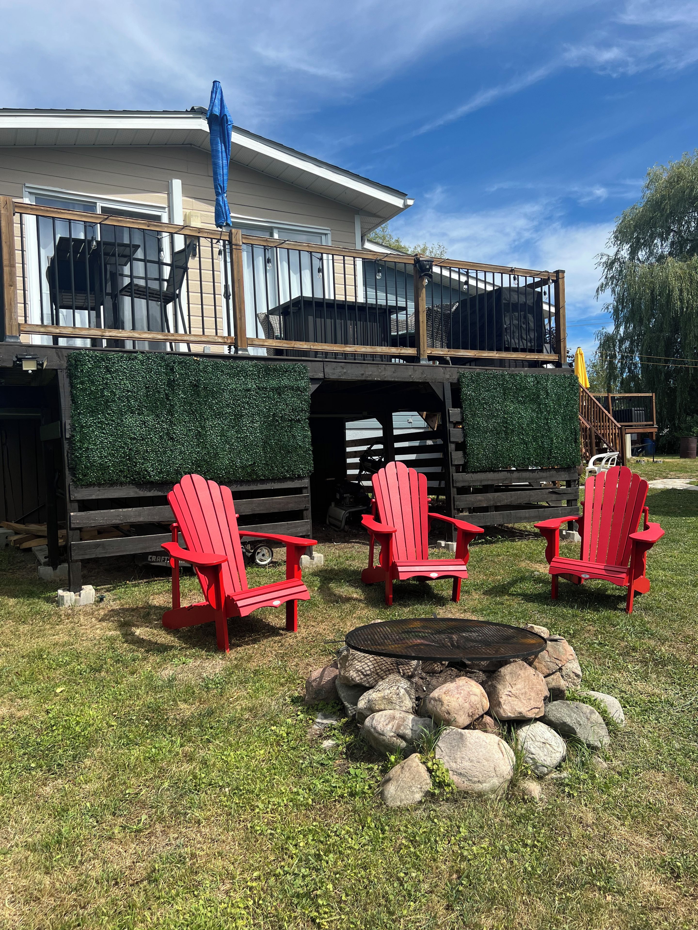 Eine Terrasse mit Feuerstelle und roten Adirondack-Stühlen.