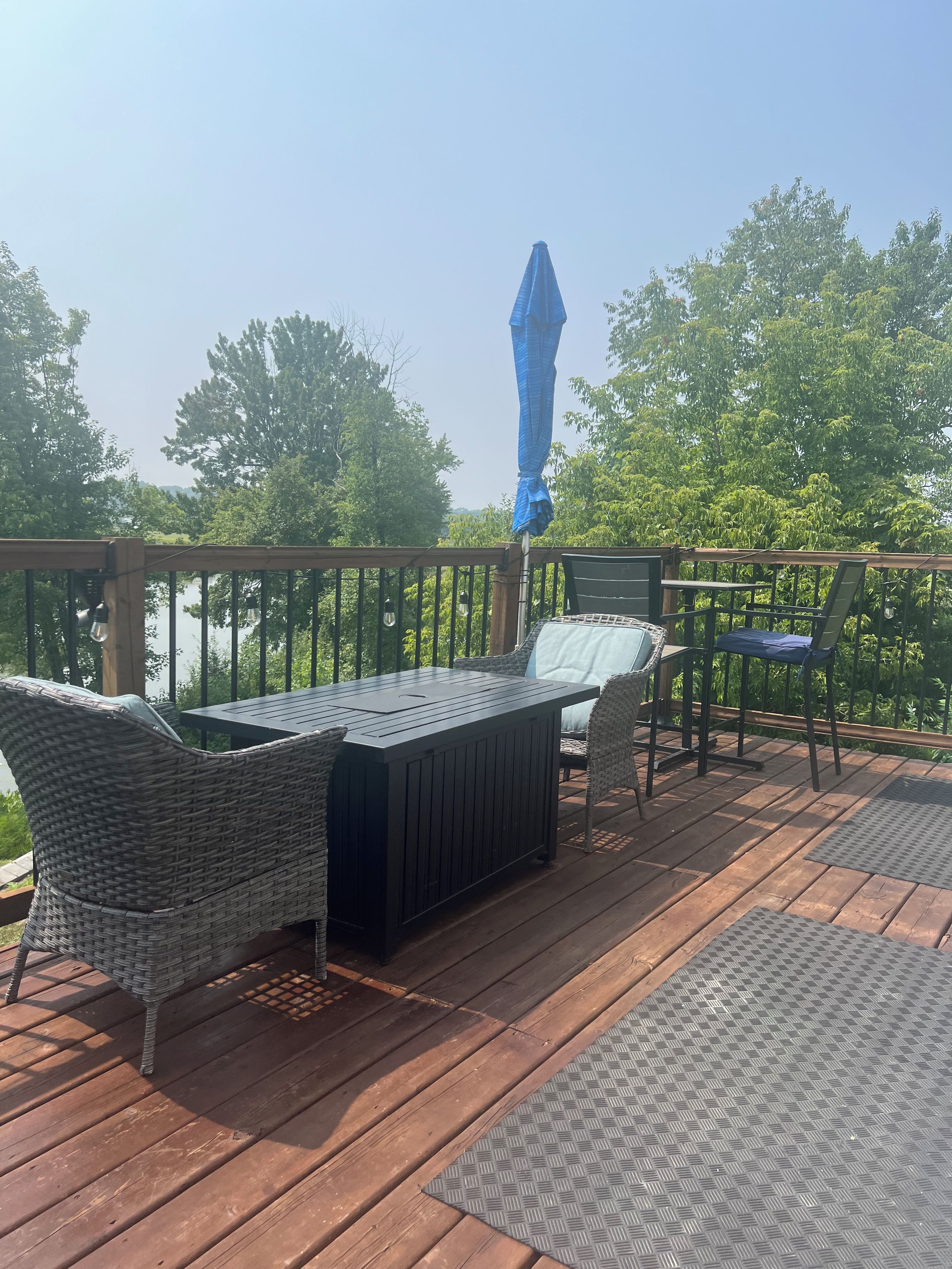 Terraza con mobiliario de mimbre y una mesa, con vista a un cuerpo de agua.
