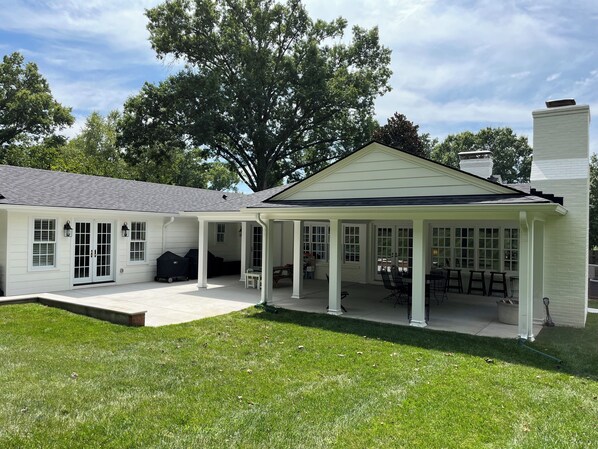 Une maison dotée d’un patio couvert, d’un espace barbecue et d’une pelouse bien entretenue.