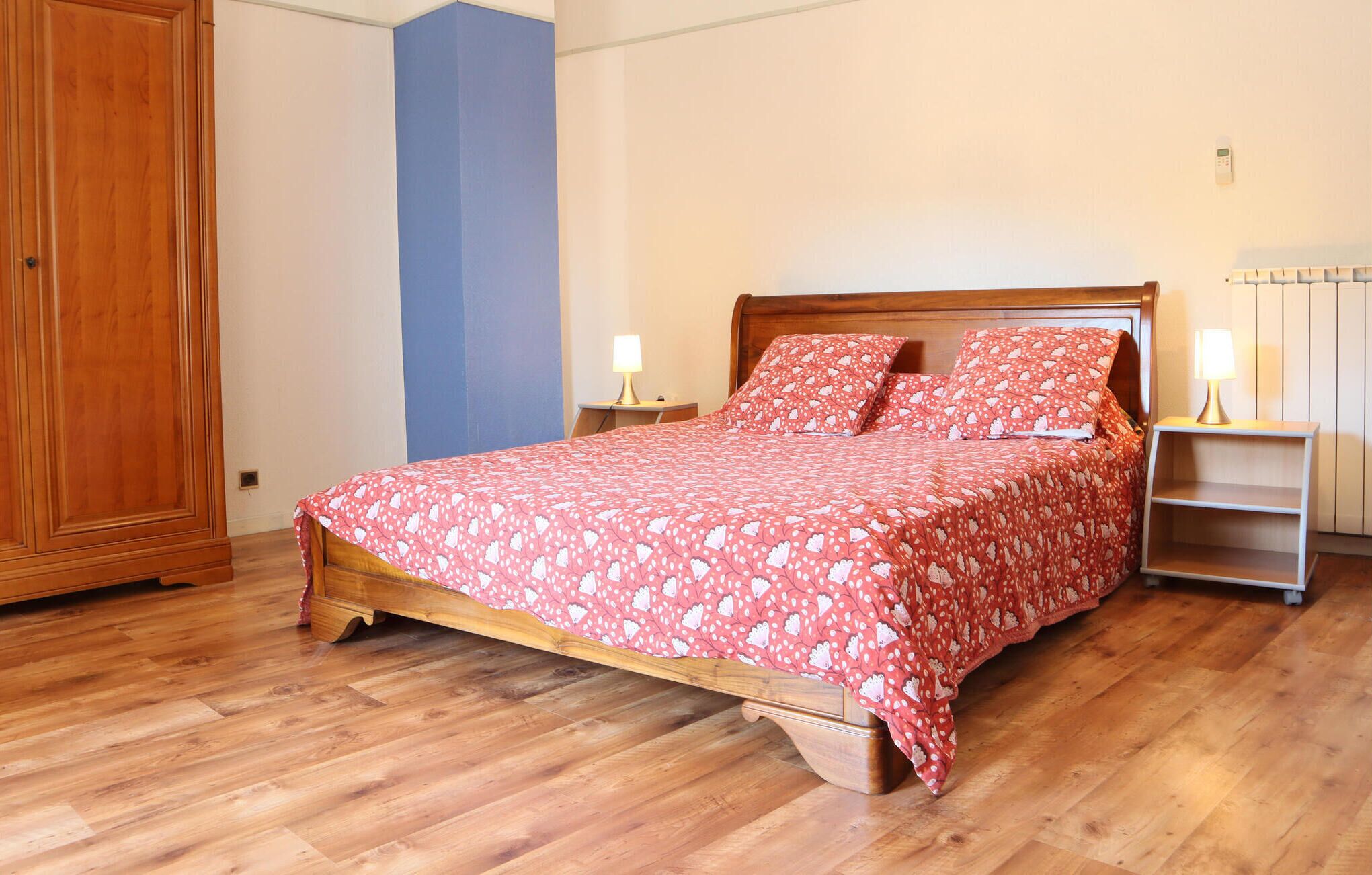 A bedroom with a wooden bed, a nightstand, a lamp, and a wardrobe.
