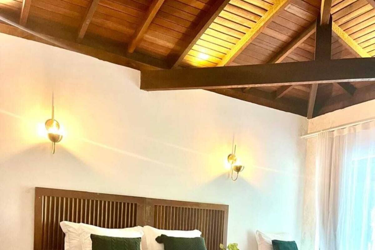 Ein Hotelzimmer mit zwei Betten, Holz-Kopfteilen und einem großen Fenster mit Vorhängen.
