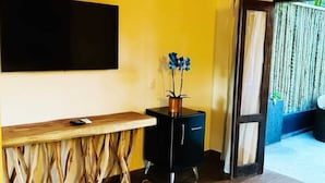 A room with a wooden table, a black cabinet, a flat-screen TV mounted on the wall, and a cowhide rug on the floor. - Villa Pantai Secret Place (Miracatu)