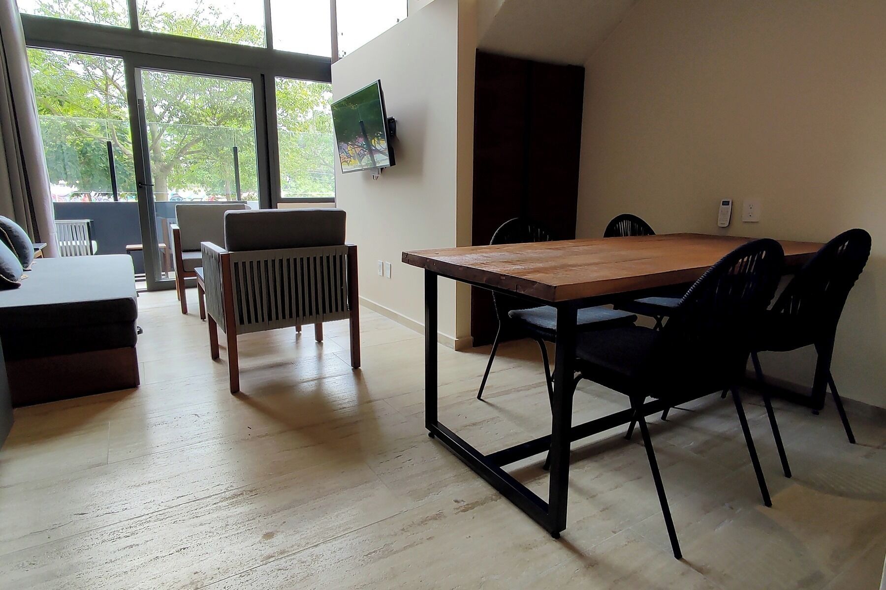 A dining area with a wooden table and black chairs, a radiator, and a TV mounted on the wall.